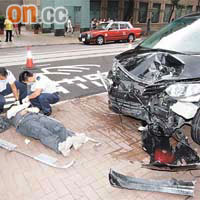 七人車失控剷上行人路嚴重損毀，其中一名男傷者倒於車前。	（馬竟峰攝）