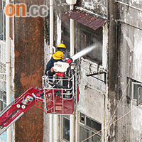 消防員升起雲梯向起火單位射水灌救。	（讀者溫先生提供）