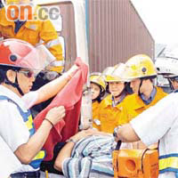 救護員將受傷被困的貨櫃車司機救出送院。	（曾紹良攝）