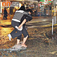 地底鹹水管爆裂引致水浸，途人孭友人涉水。	（鄭家如攝）