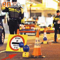 警方在設路障時，會以藍色閃燈（箭嘴示）協助指引道路使用者。	（資料圖片）