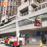 消防員架起升降台，由行人天橋頂將母子的屍體抬下。