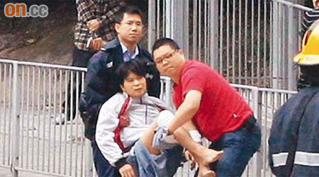 救人英雄鄧少鴻（右）與警員合力抬走傷者。