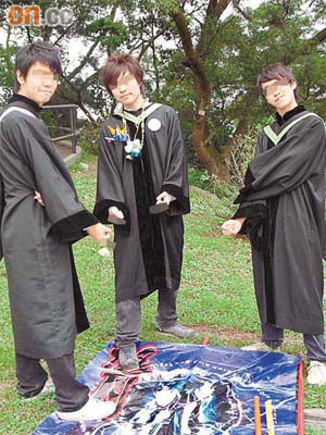 三名穿上畢業袍的疑似中大學生踩旗及伸出中指動作拍照。