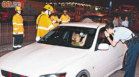 警員與消防員拍窗叫喚仍無法叫醒司機。	（楊偉嶽攝）