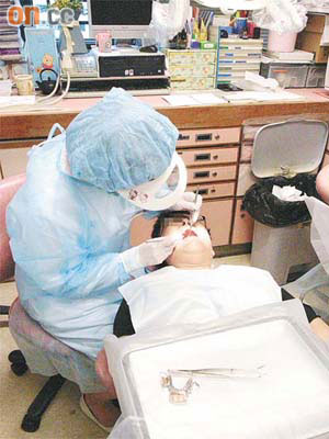 涉「剝錯牙」的牙醫與助護在記者「監視」下為病人補牙，疑因心虛顯得「手騰腳震」。	（吳啟偉攝）