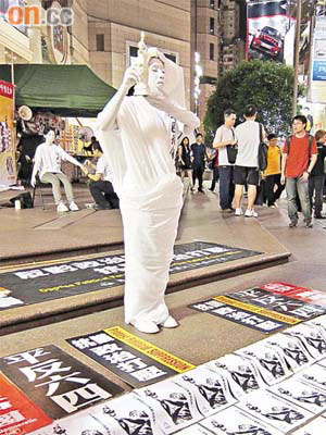 青年昨晚在時代廣場露天廣場全身塗上白色扮演「民主女神像」。（翁志偉攝）