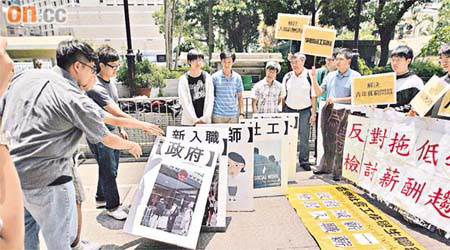 學生推倒發泡膠骨牌，寓意一旦新入職公務員減薪，私人市場亦會跟隨，造成骨牌效應。	（高嘉業攝）