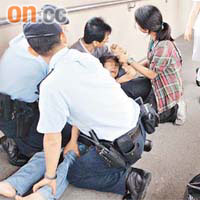 女事主極力掙扎，丈夫與警員合力將她按在地上安慰。