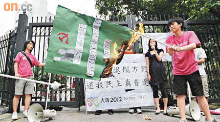 「大專2012」約十人於政府總部外焚燒代表政改方案的旗幟，促請港府撤回方案。	（高嘉業攝）