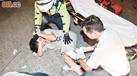 踏單車少年受傷倒地呻吟，救護員為他急救。（梁國雄攝）