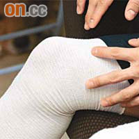手術後的左膝綁上厚厚繃帶，右膝則套上護膝。