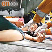 女事主被夾在電車車頭下，救護員為她包紮頭部傷口。	（馬竟峯攝）