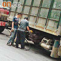 兩名男子拿着油槍為貨車入油。