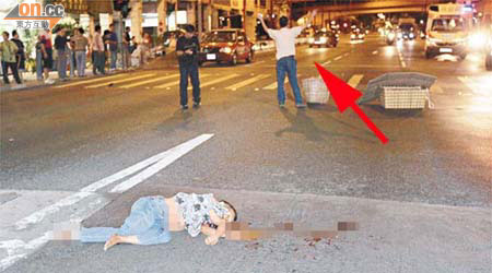 老婦被車撞後倒臥路中，好心男子走出馬路舉起雙手攔車（箭嘴示）。	（胡德威攝）