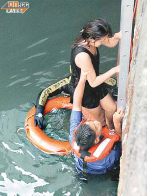獲救女子渾身濕透，由消防員用鋁梯給她爬返岸上。