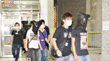 在天平邨被捕五名男子由警員蒙頭帶走。	（吳建明攝）