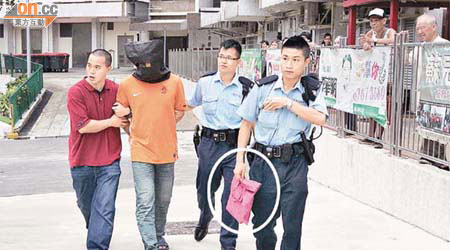 警員將被捕男子蒙頭帶署，並用袋載走菜刀（圓圈示）作證物。	（冼耀華攝）