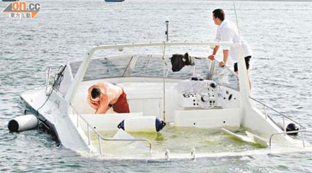 兩名外籍男子堅持留守入水的遊艇，惟最終仍告沉沒。	（許錦雄攝）