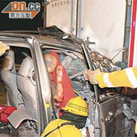 消防員在車頭嚴重撞毀的七人車營救被困司機。