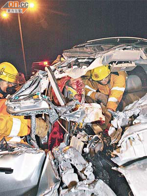 消防員在車頭嚴重撞毀的七人車營救被困司機。