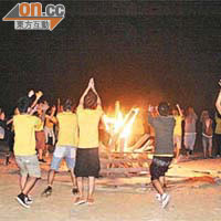 一群年輕人圍着正在燃燒的木架載歌載舞及玩遊戲。	（互聯網圖片）