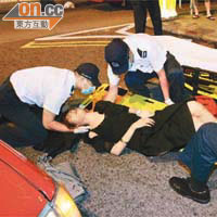 穿高跟鞋女子腰部受傷臥在地上接受救護員包紮。	（胡德威攝）