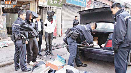 警員押解涉案兩名青年搜查房車，發現一批手袋及衣物。	（冼耀華攝）