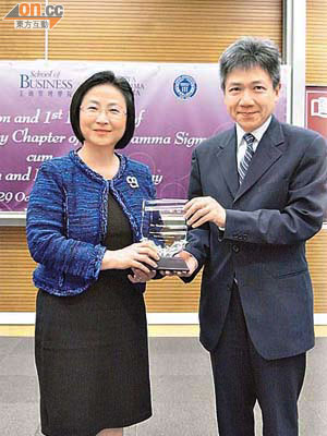梁高美懿（左）從浸大工管學院院長張仁良手中，接過「Beta Gamma Sigma 香港浸會大學分會」終身會員嘅獎座。	（楊歡成攝）