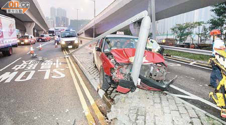 的士險被塌下燈柱壓中車頂，車頭毀爛不堪。	（蕭偉健攝）