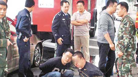 兩名男疑匪被制服後坐在地上，而姓黃港商（後排中）則向一名消防官講述事件經過。