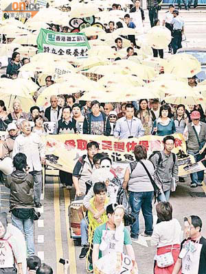 逾百名長者及市民高舉雨傘，以示「全民起動撐退保」。