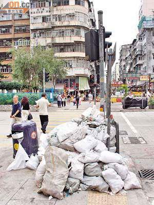街角垃圾桶在建築廢物堆放下被迫移位，遭推至行人路中央。