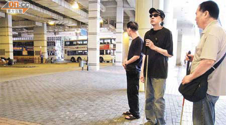 在欠缺引路徑之下，歐光宗（右）與其他視障人士無法辨別候車站位置。