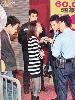 涉案女遊客在場回答警員查問，帶有醉意的男遊客則站在其身後。	（張曉楠攝）