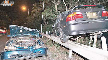 兩車相撞後，其中一輛私家車擱在鐵柱上。	（左蘭慶攝）