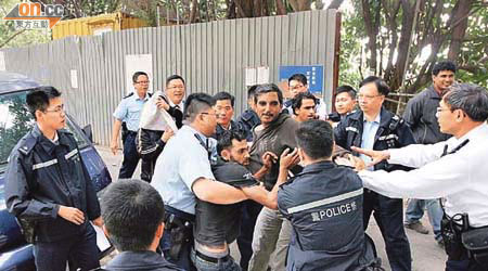 遭欠薪的南亞裔工人，在荃灣地盤外企圖衝向判頭，警員連忙阻止。	（吳子生攝）