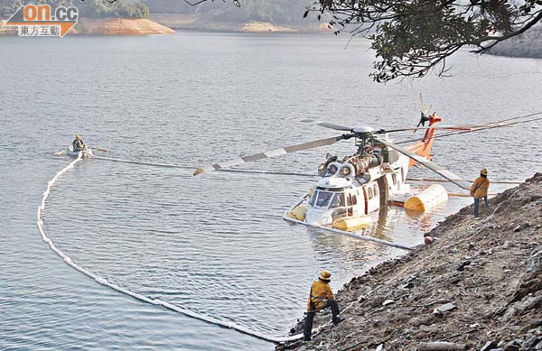 當局人員在肇事直升機外圍放置隔油條，確保水質不受污染。 （翁志偉攝）