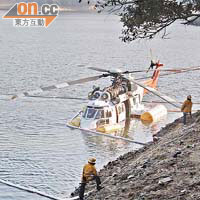 當局人員在肇事直升機外圍放置隔油條，確保水質不受污染。	（翁志偉攝）