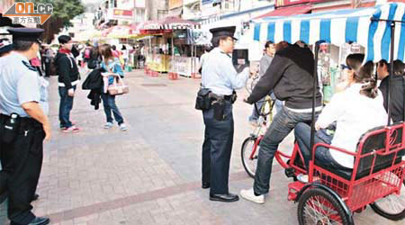 警察截停載人的三輪單車，指示他們下車。