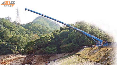 重型吊車伸出廿米長吊臂落水塘將直升機吊起。	（陳展鴻攝）