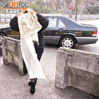 包志雄妻子用白色披肩由頭包到腳，恐防被攝入鏡頭。	（鍾建國攝）
