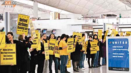 聯合航空空中服務員工會代表在機場離境大堂聯合航空櫃位對開進行無聲抗議。	（羅錦鴻攝）