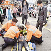 受傷內地女遊客倒臥地上，仁醫（右）及救護員為她急救後送院。