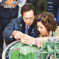 陳智思（左）喺製衣員輔助下操作縫盤機，自嘆技不如人。