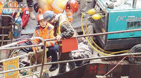 兩名工人被鐵板壓傷倒地接受治療。	（馬竟峯攝）