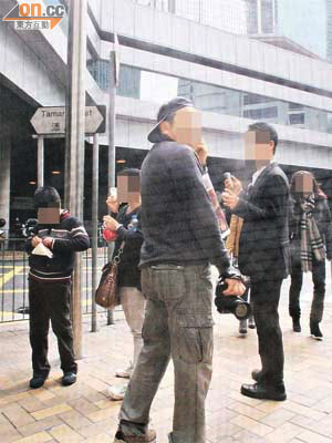 一名男子（中）在金鐘港鐵站外，不停向未能購票的旅客兜售門票。