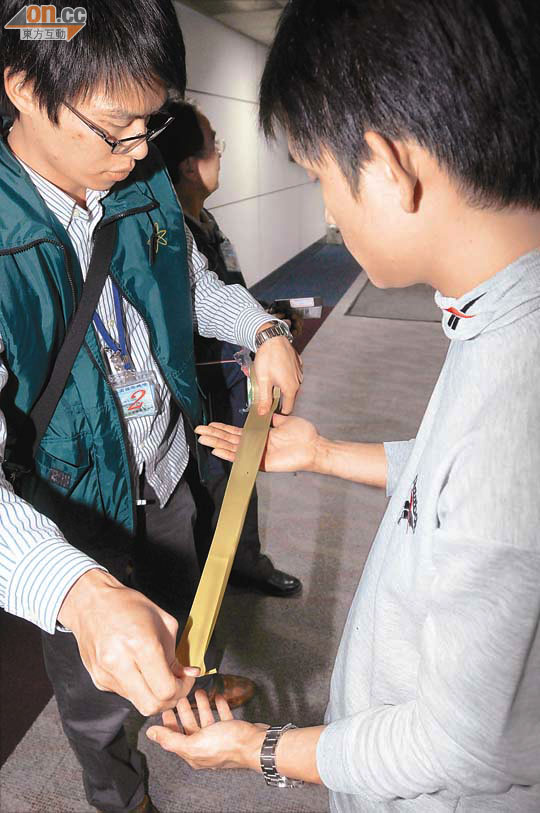 工作人員用封箱膠紙清除留日學生手上的輻射污染。 （本報台北圖片）