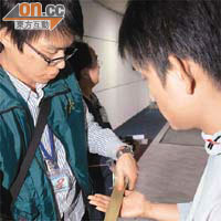 工作人員用封箱膠紙清除留日學生手上的輻射污染。	（本報台北圖片）