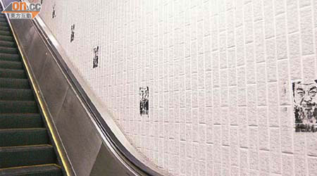 通往九龍公園徑的扶手電梯牆身，被噴上多個艾未未塗鴉肖像。 	（梁卓明攝）